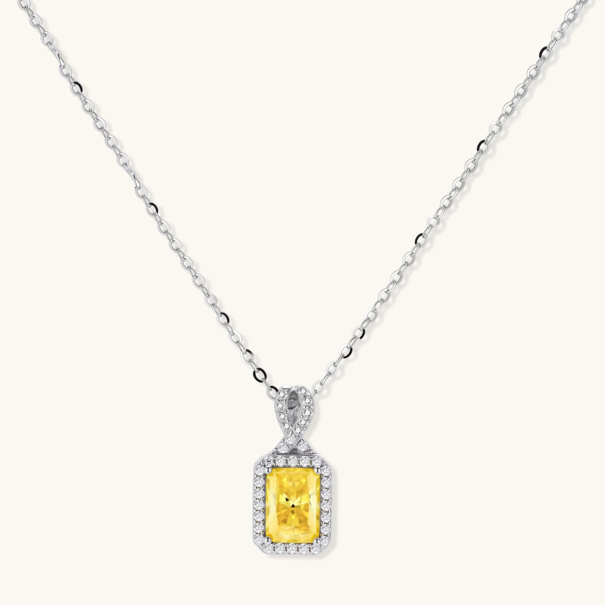 Platinum-plated 925 sterling silver necklace with a yellow radiant-cut moissanite pendant in a sparkling halo on a cream background.