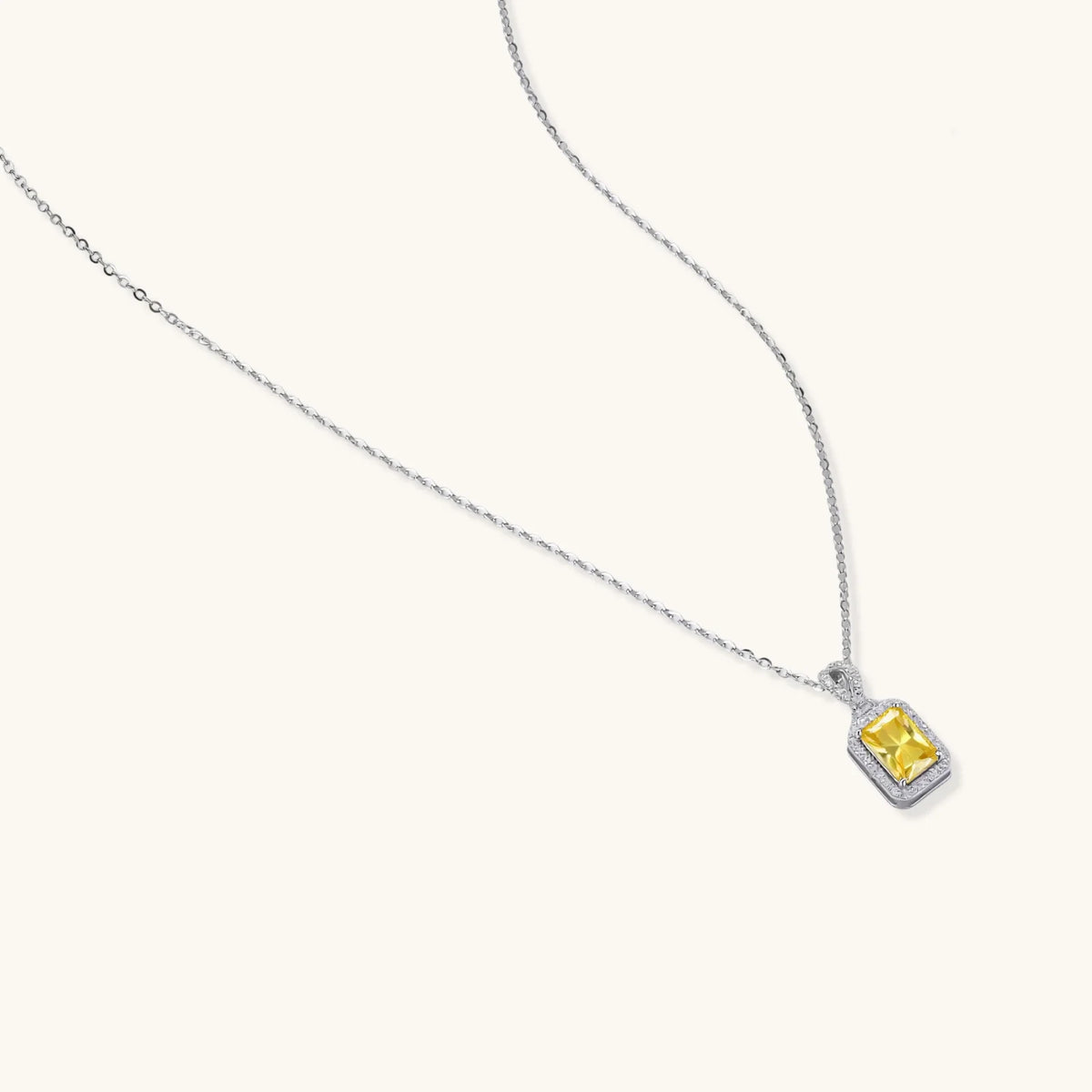 Platinum-plated 925 sterling silver necklace with a yellow radiant-cut moissanite pendant in a sparkling halo on a cream background.