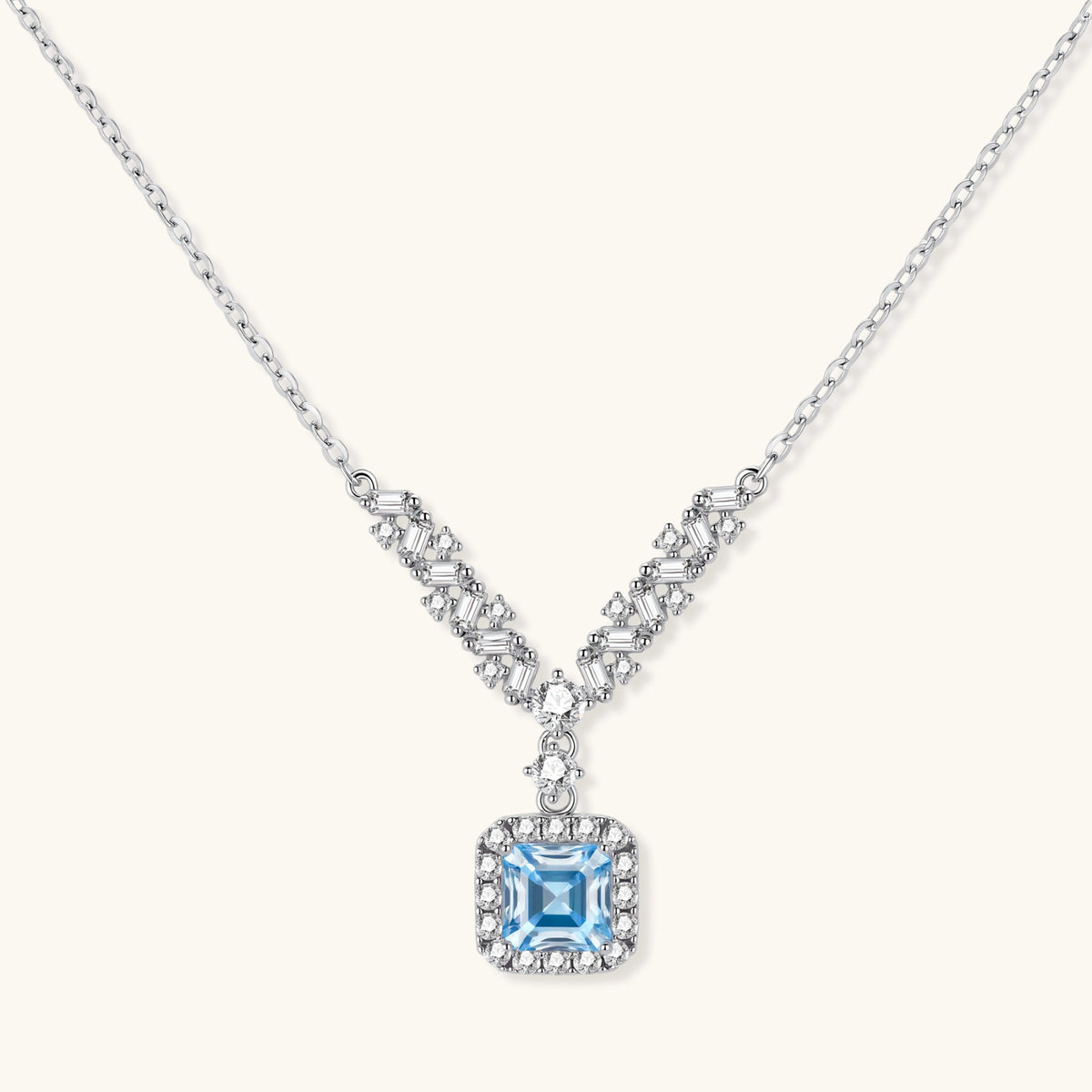Sterling silver necklace with geometric crystal arrangement forming a V-shape and square blue moissanite centerpiece pendant
